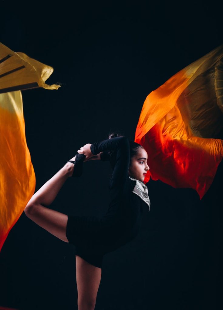 Elegant young gymnast striking a pose with vibrant flowing fabric.