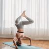 A woman in activewear performing a yoga headstand indoors, showcasing strength and balance.