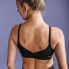 Young woman in activewear showing back muscles against a purple background.